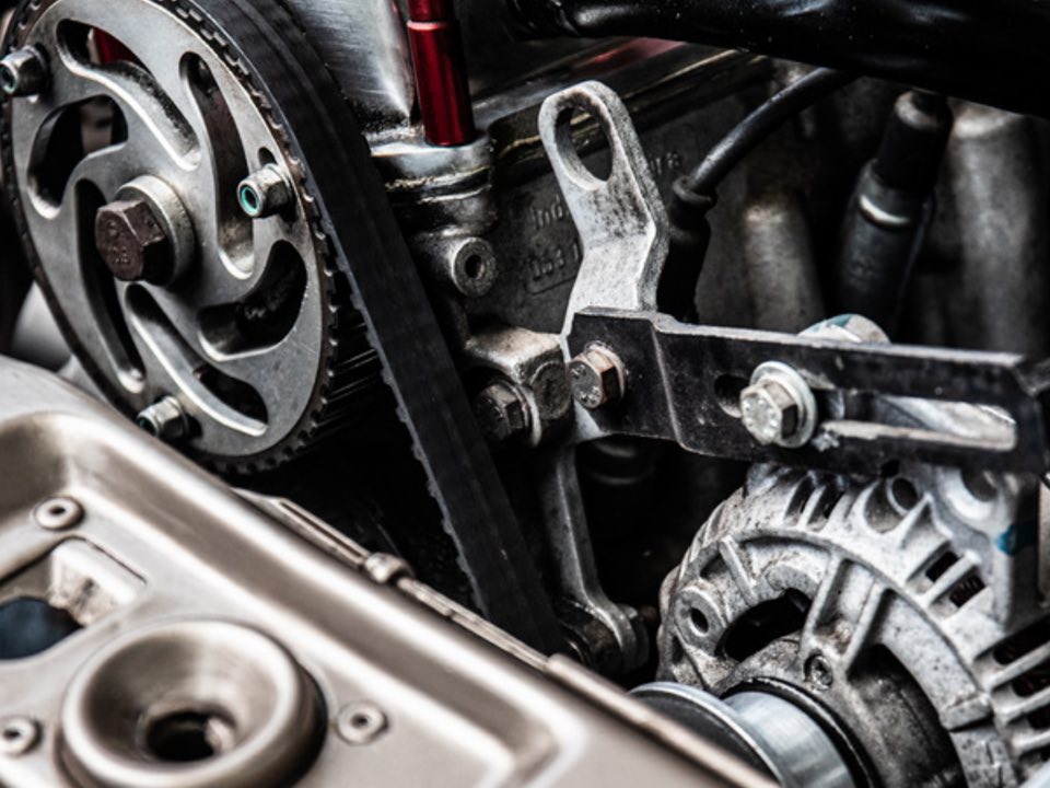 The cambelt, pulley and alternator of a car engine exposed during a timing belt replacement.