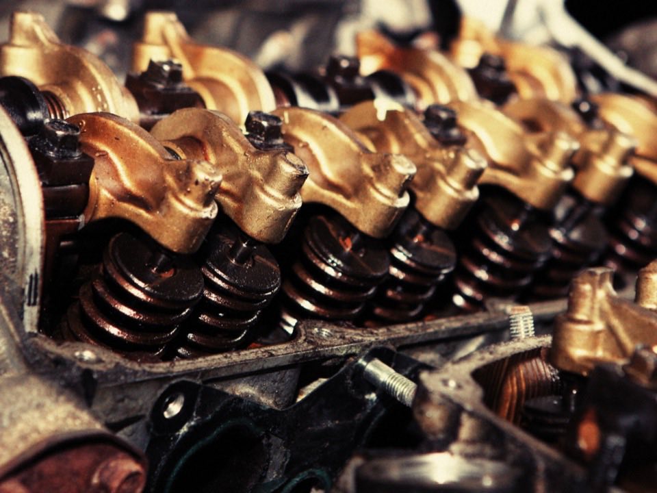A cylinder head with the rocker arms and valve springs exposed during an engine repair.