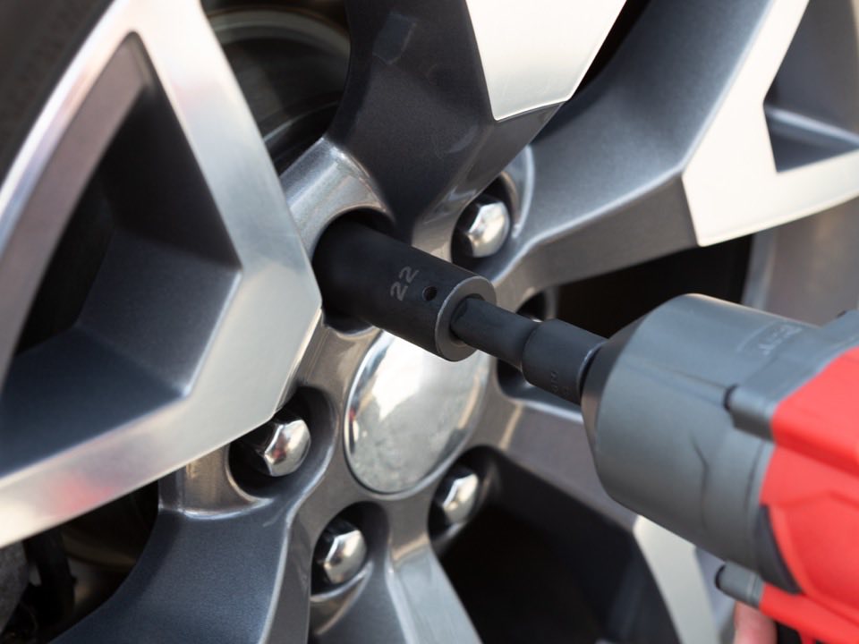 An impact wrench loosening the wheel nuts on an alloy wheel during a tyre rotation.